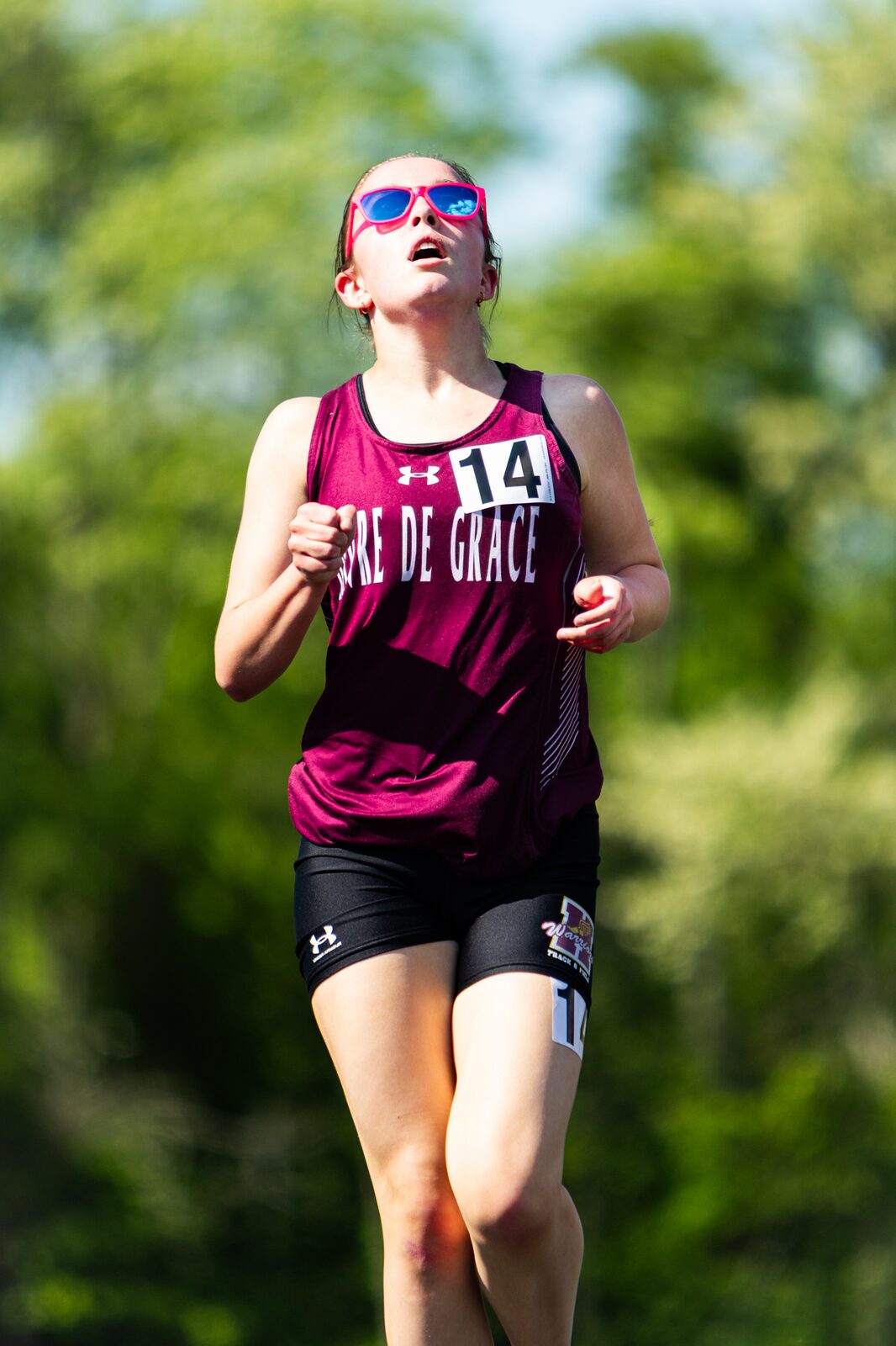 Distance runner in sunglasses coming toward the camera mid race