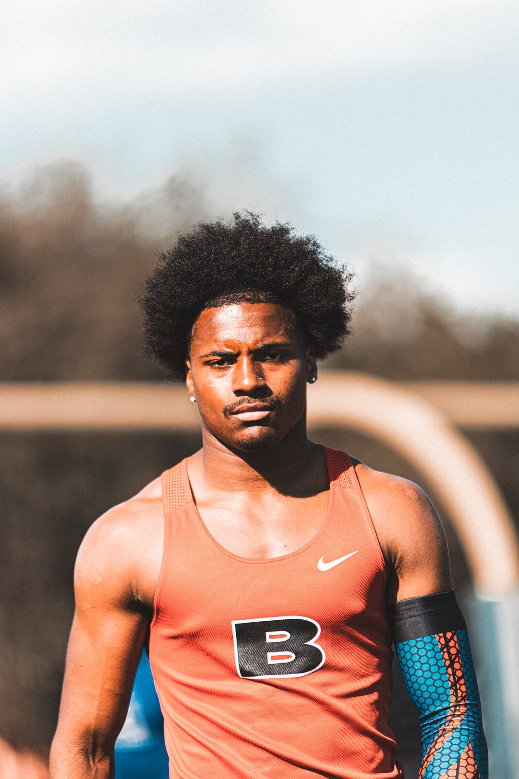Portrait of a sprinter in an orange singlet looking off camera