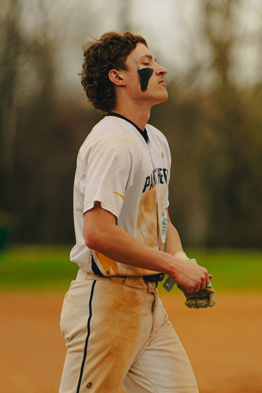 Player walking off the infield in a dirt stained uniform holding his glove
