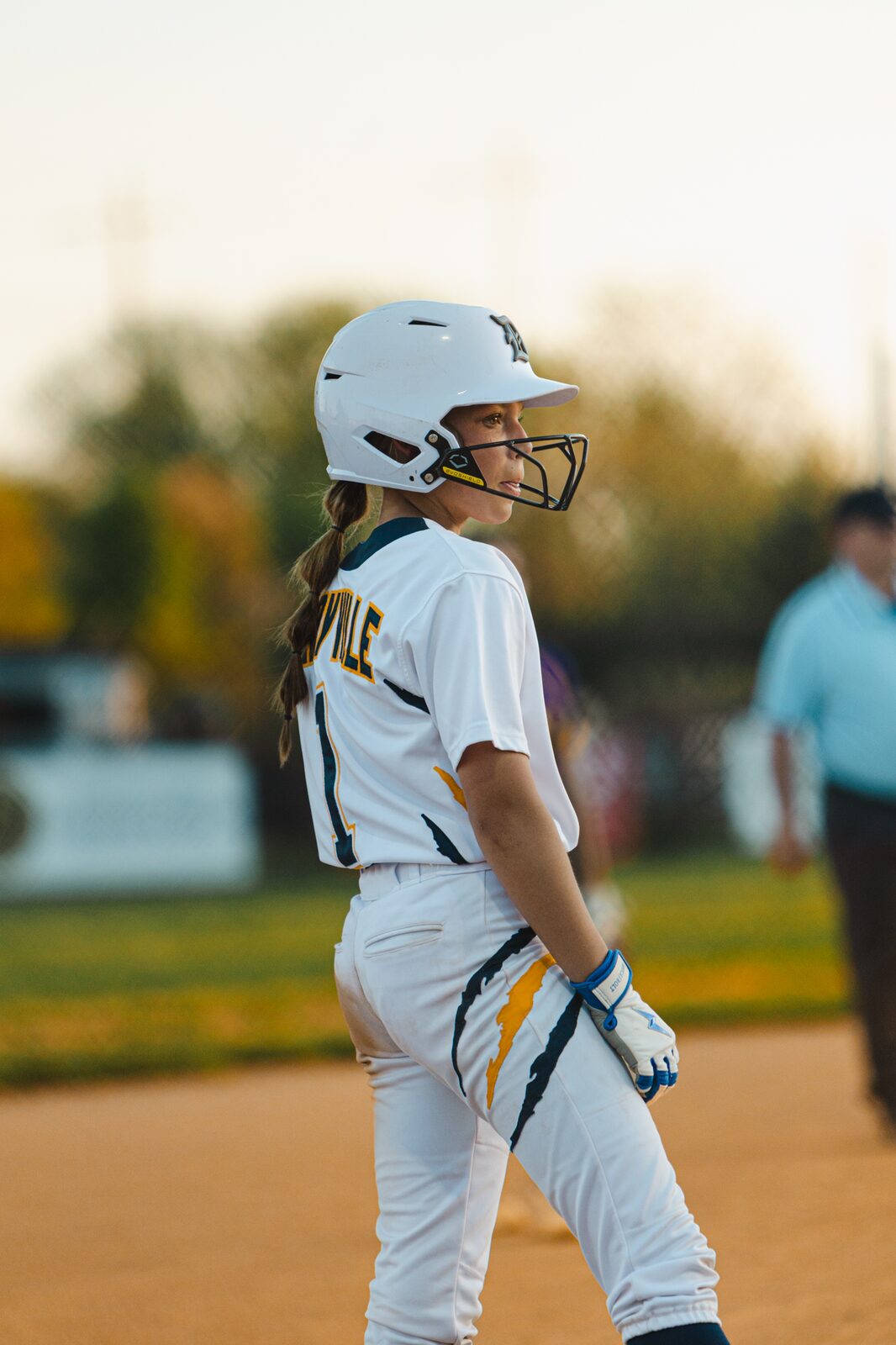 Softball player walking toward the batter's box in warm evening light