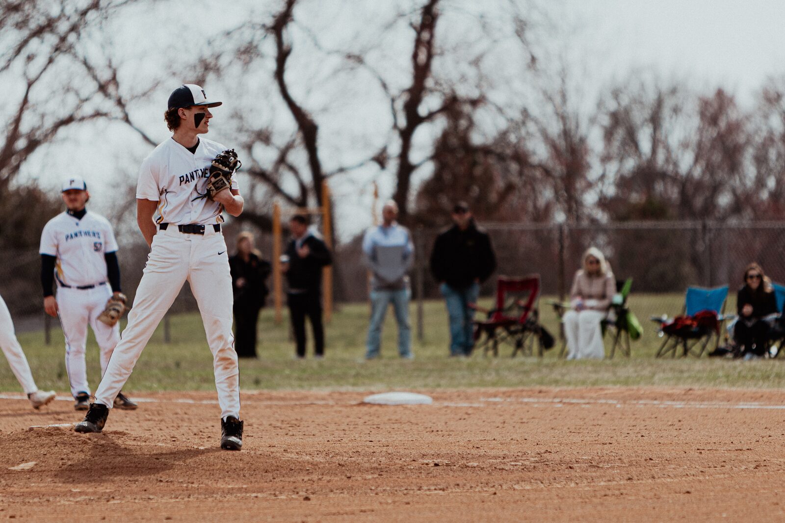 Pitcher on the mound with families watching along the fence line
