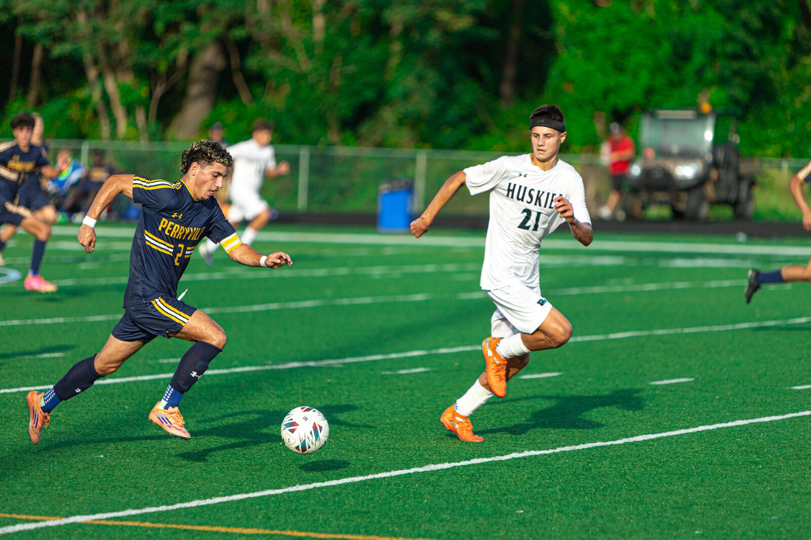 Two soccer players sprinting stride for stride as they battle for the ball at midfield
