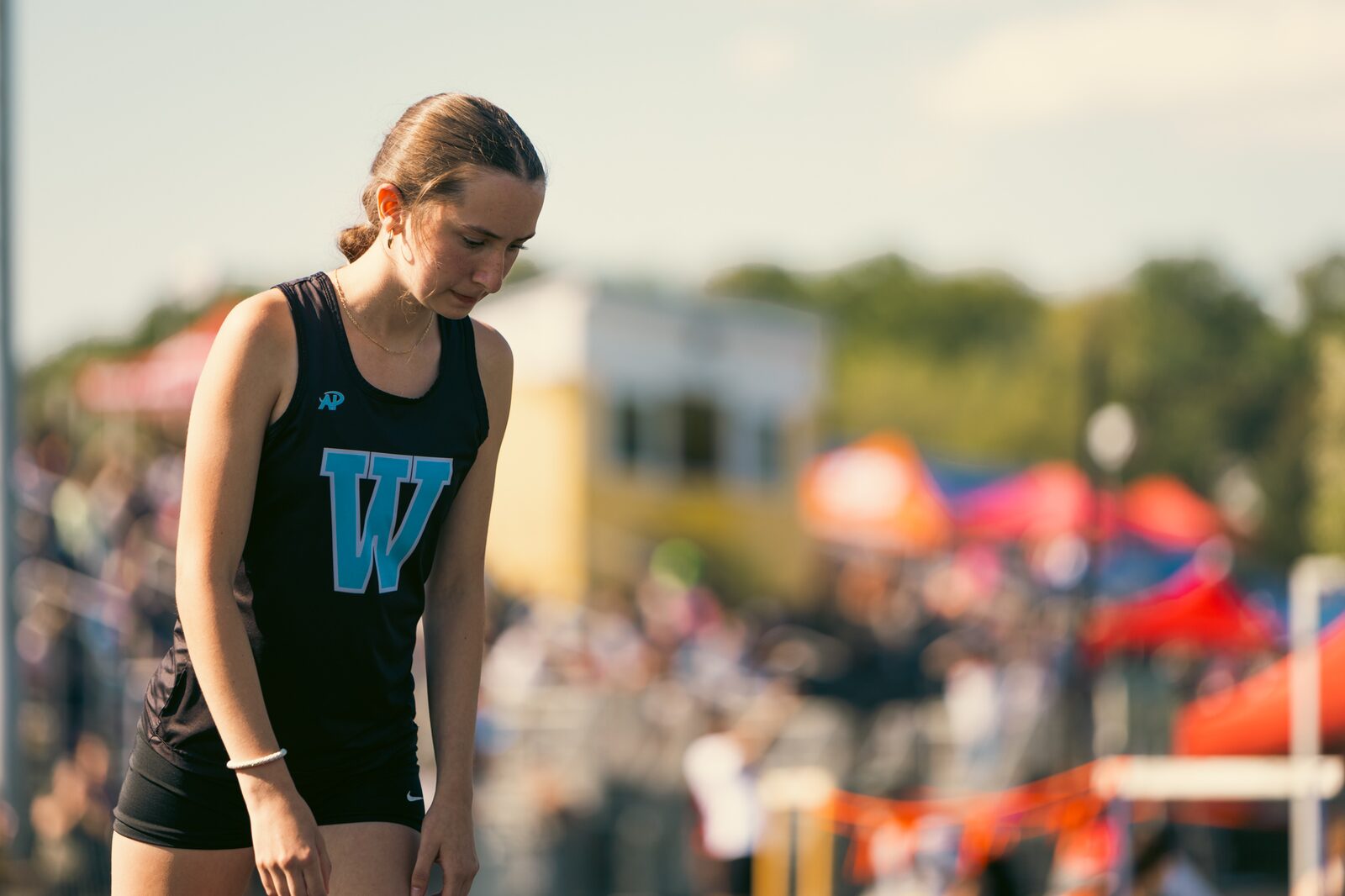 Athlete with her head down in front of a crowded infield between events