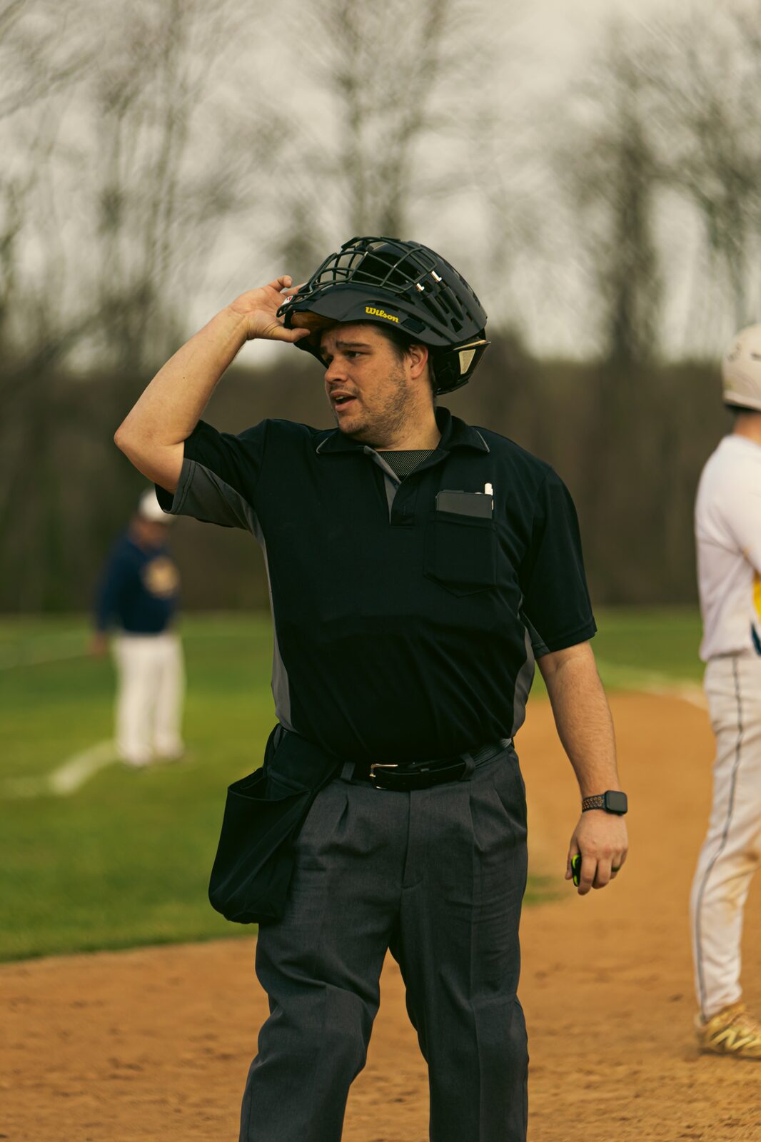 Umpire adjusting his mask behind the plate between innings