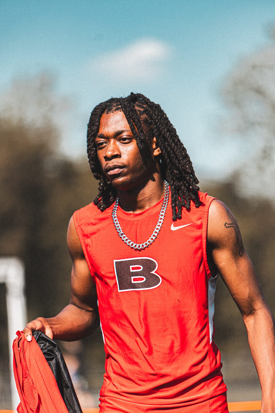 Portrait of a sprinter in a red singlet looking toward the track before his race