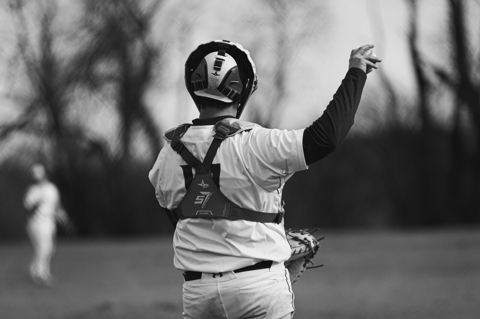Black and white photo of a catcher throwing his arms out behind the plate