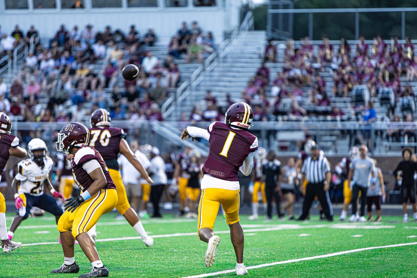 Quarterback releasing a pass with a packed student section filling the stands behind him