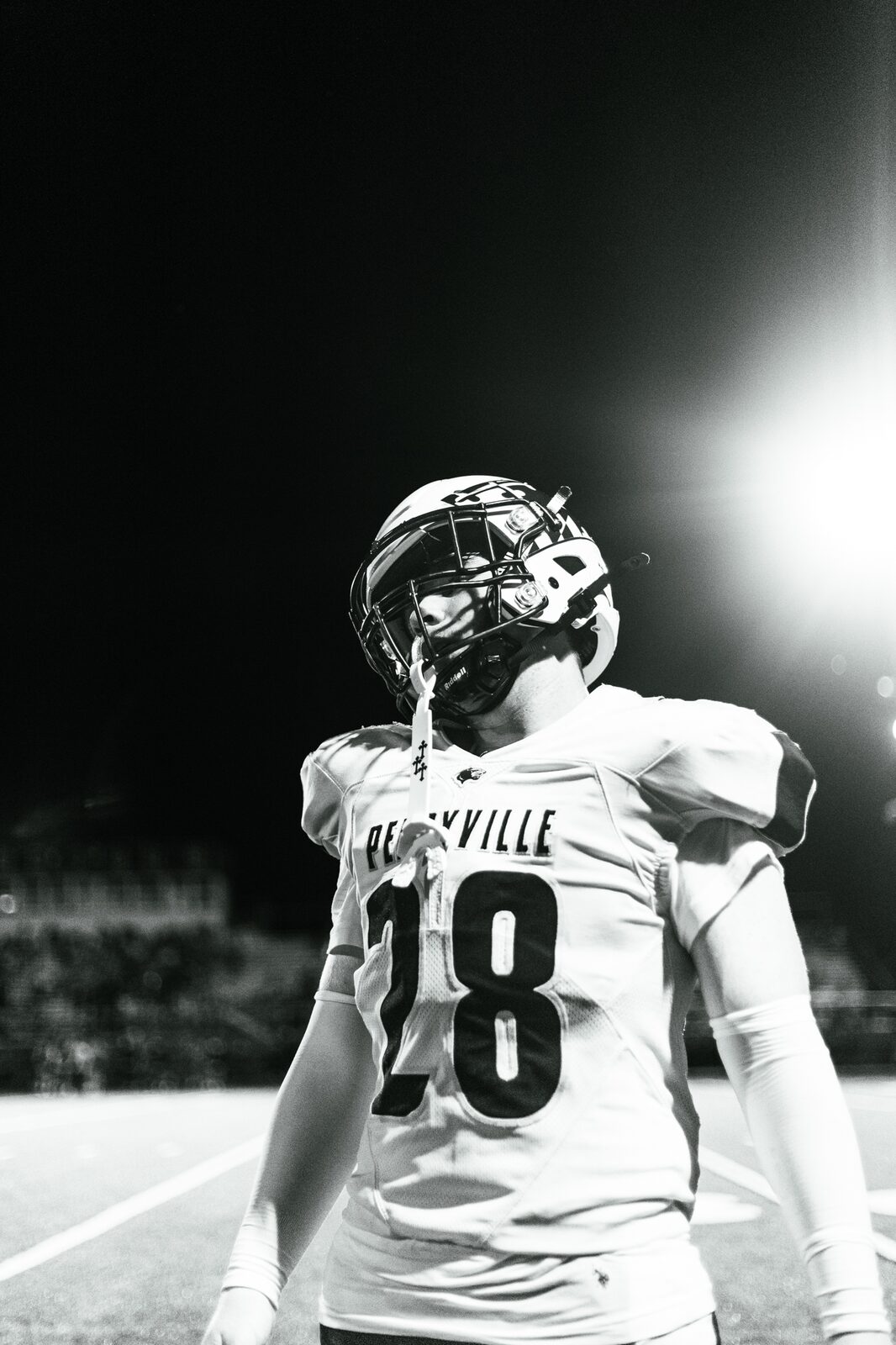 Black and white portrait of player number 28 looking down the field under bright stadium lights