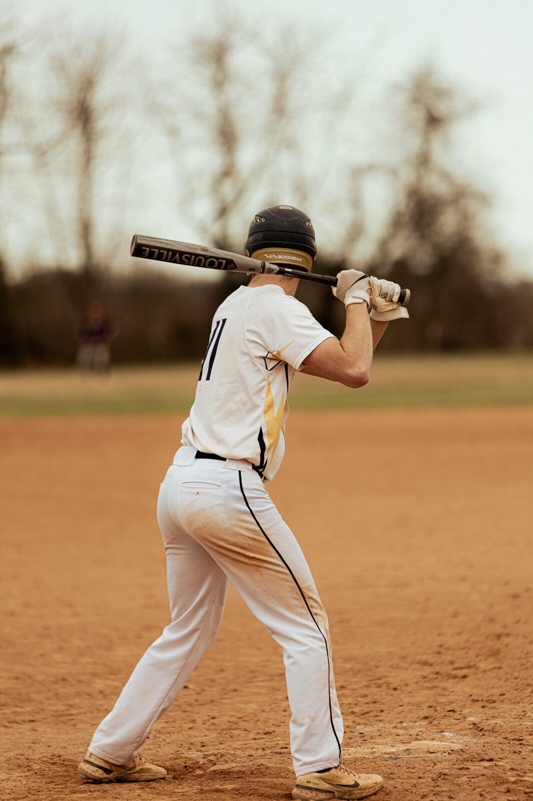 Batter set in his stance at the plate seen from behind
