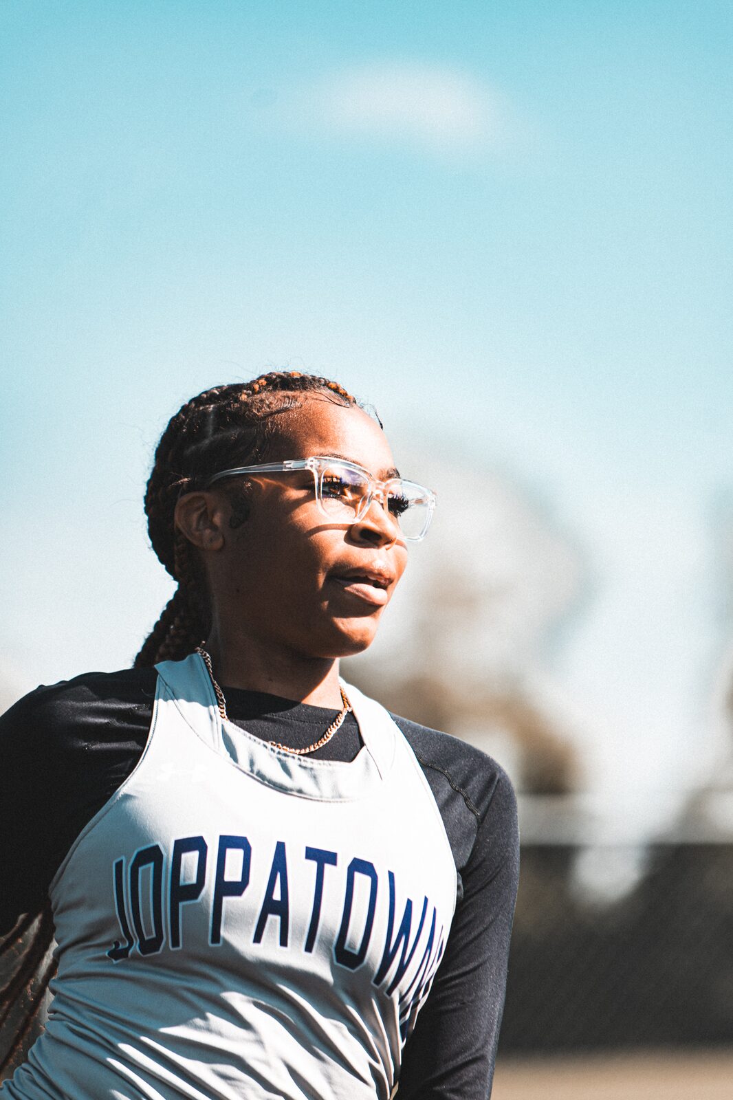 Portrait of a sprinter in a white and grey singlet looking toward the track