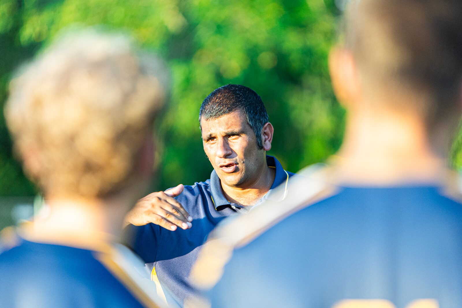 Soccer coach with his hand on a player's shoulder giving instructions on the sideline