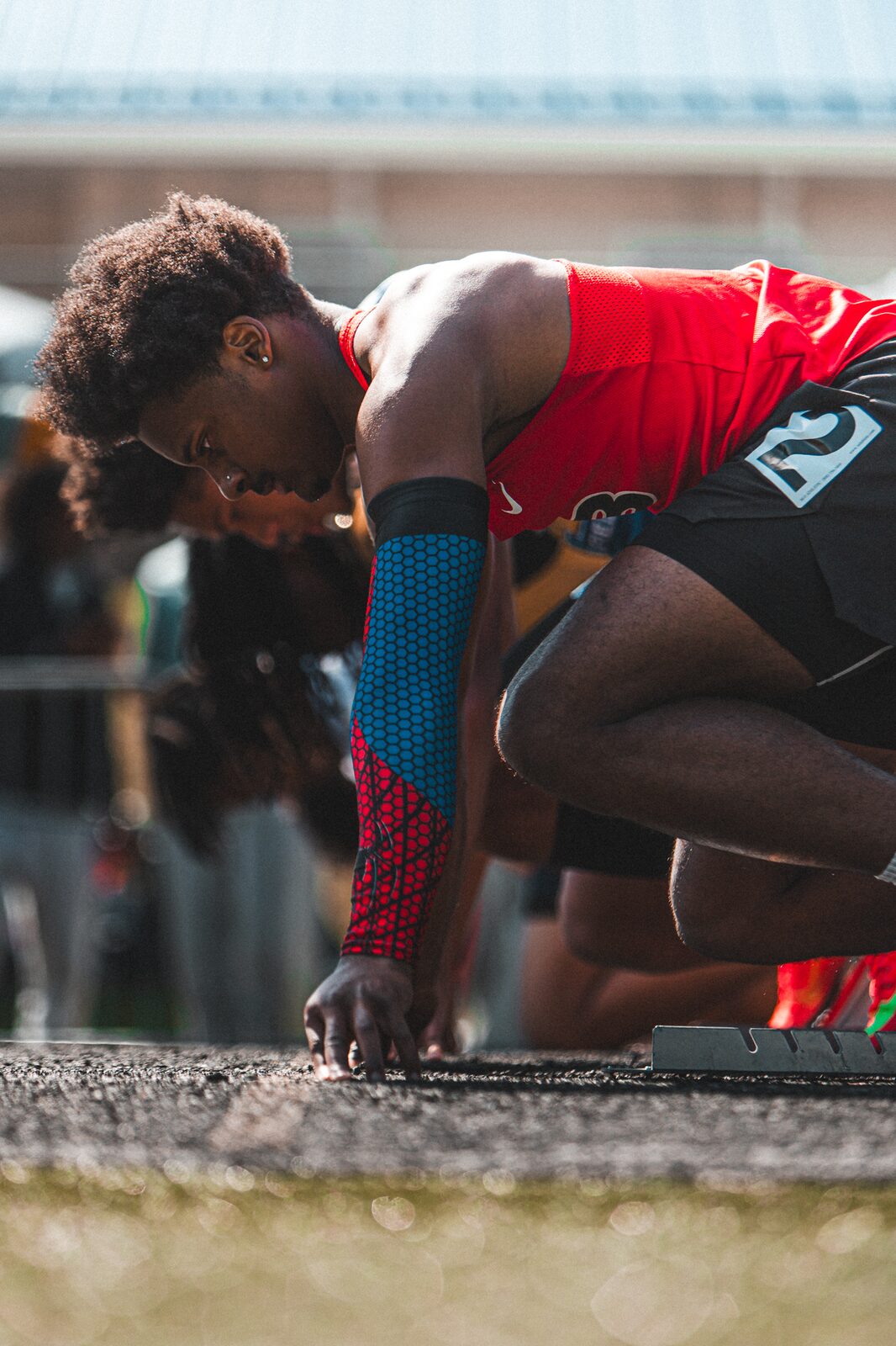 Sprinter set in the starting blocks with his fingertips on the line