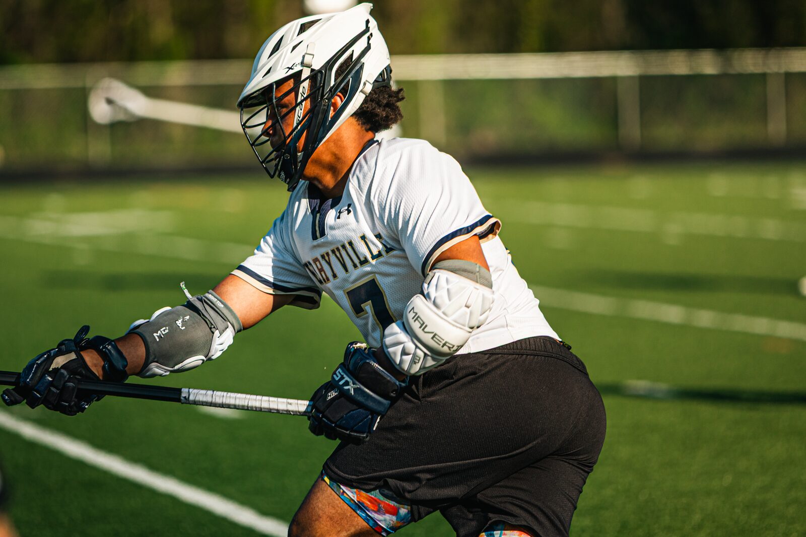 Lacrosse player driving toward the goal while a defender trails him