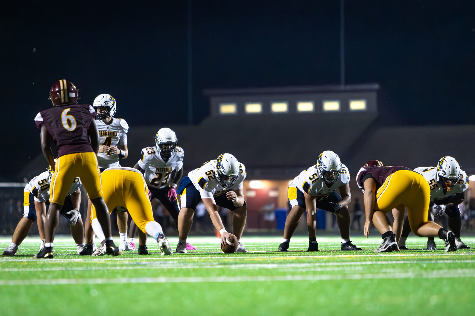Offense and defense set across the line of scrimmage under the lights before the snap