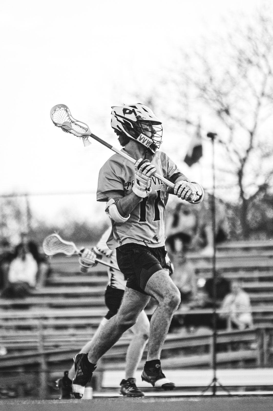 Black and white photo of a lacrosse player loading up for a shot