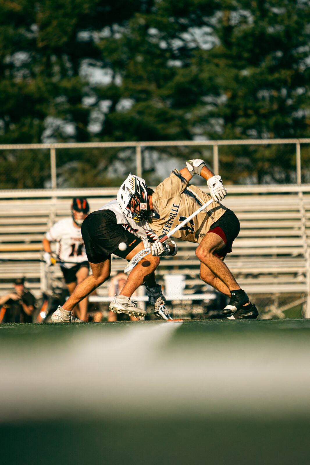 Two lacrosse players crouched low against each other on the faceoff X waiting for the whistle