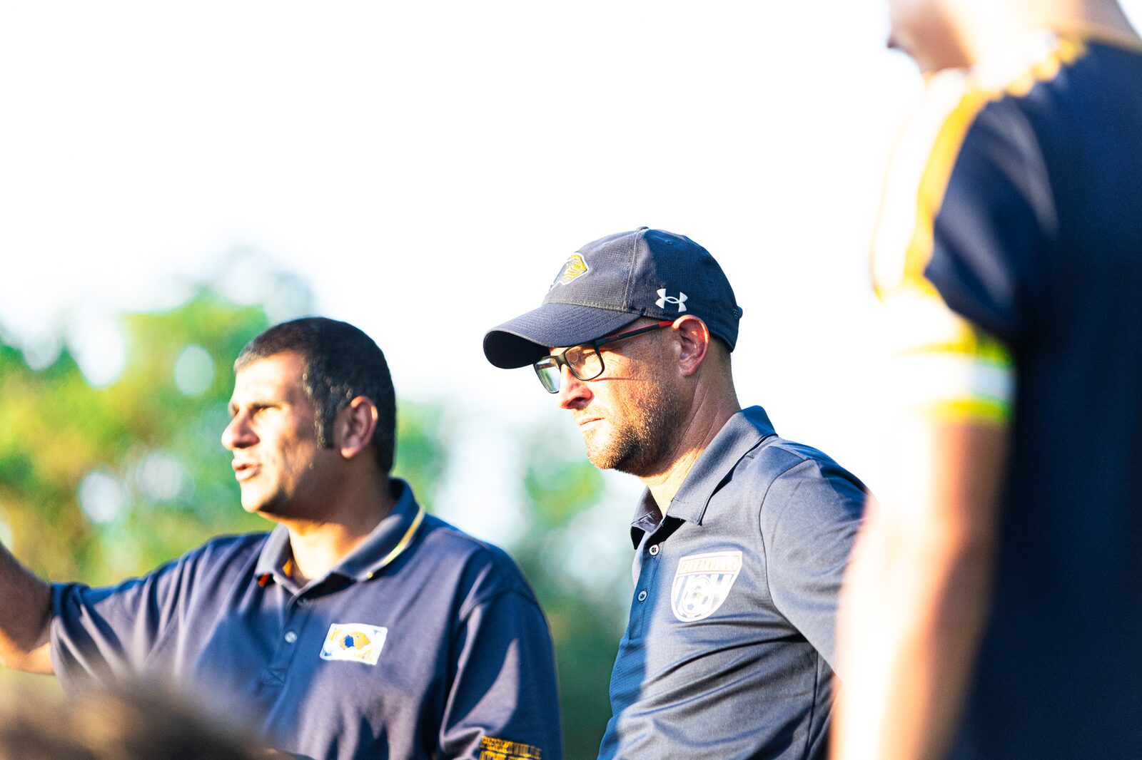 Two soccer coaches talking on the sideline during a match
