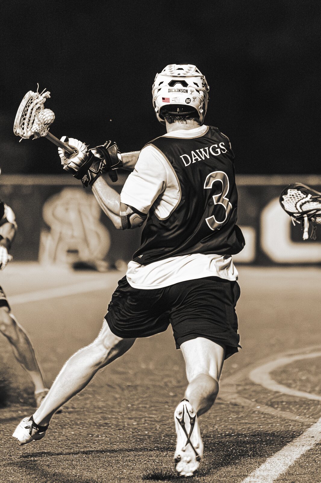 Sepia toned photo of a lacrosse player running up the field with the ball
