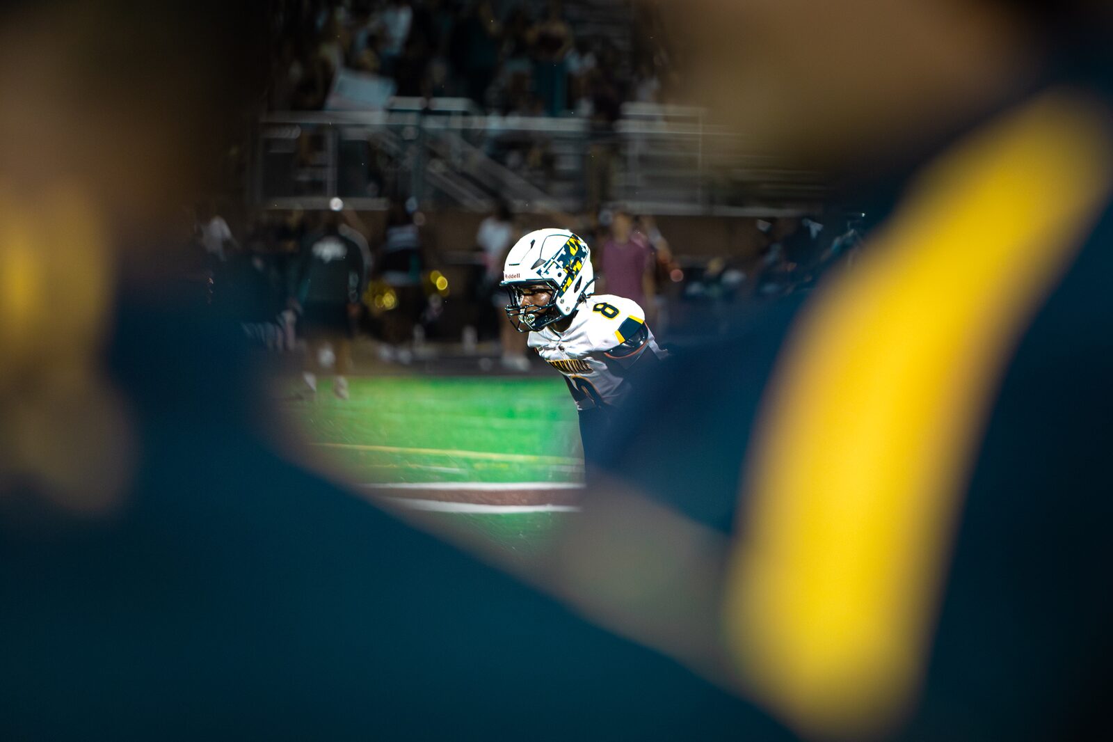 Player framed through a blurred helmet in the foreground during a night game