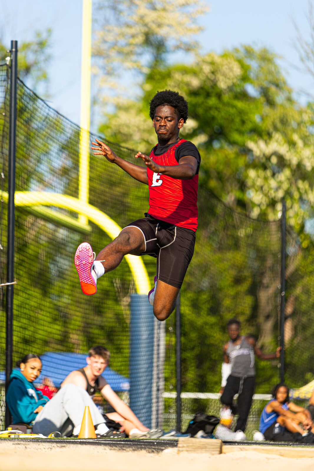 Long jumper stretched out in mid flight above the sand pit