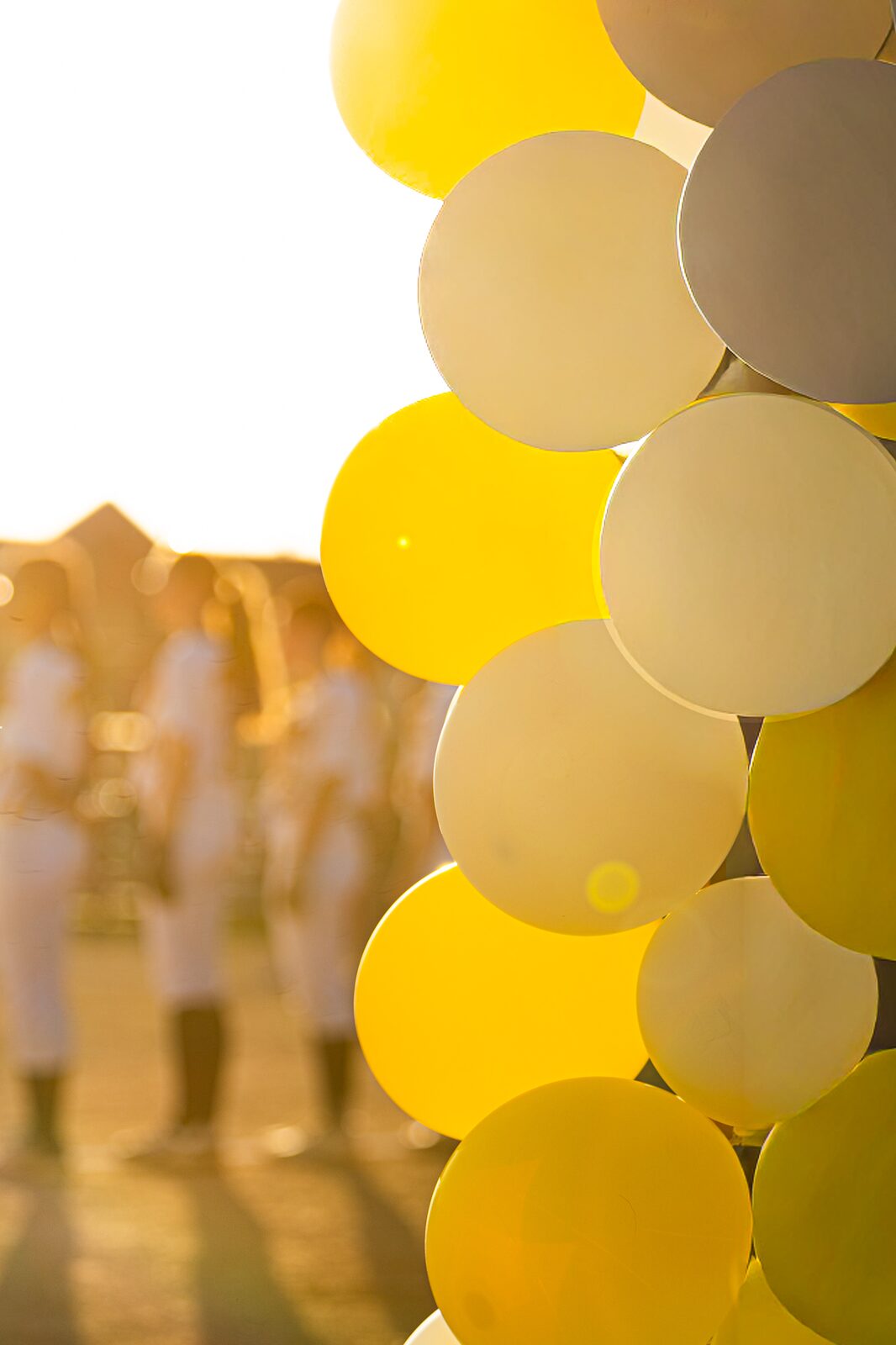 Gold and white balloons in the foreground with players gathered on the field behind them
