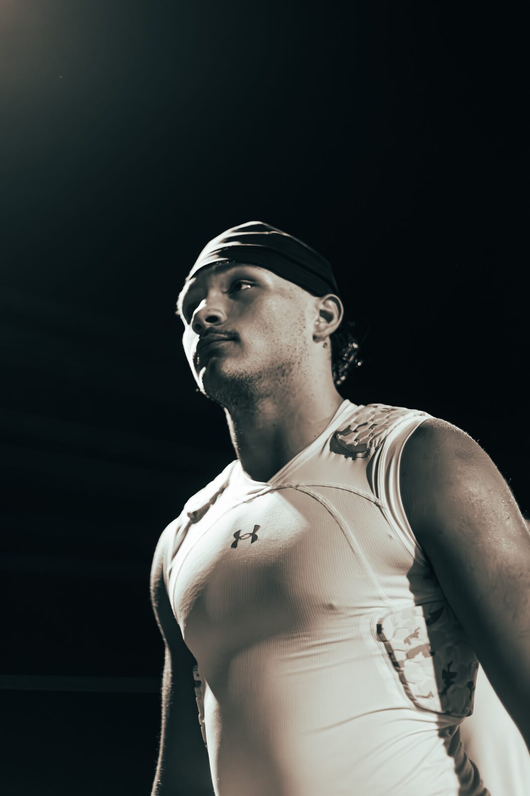 Low-key portrait of a player in a compression shirt looking off camera against a dark background